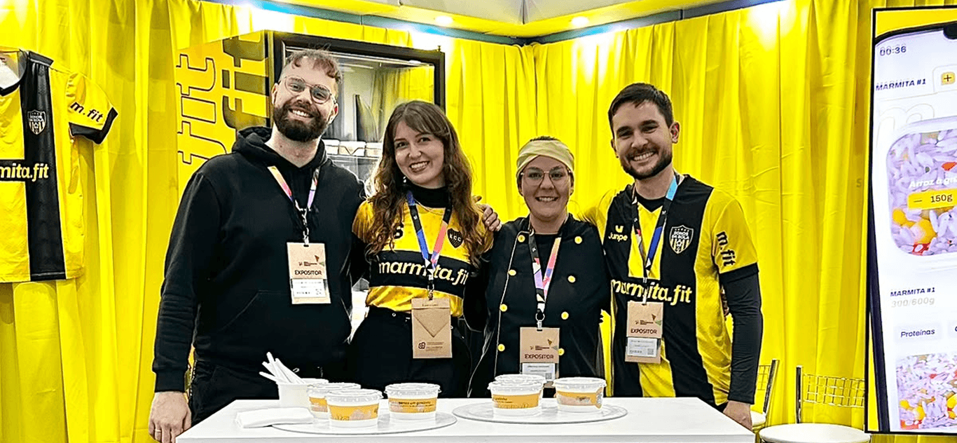 The marmita.fit team at an event booth, handing out samples